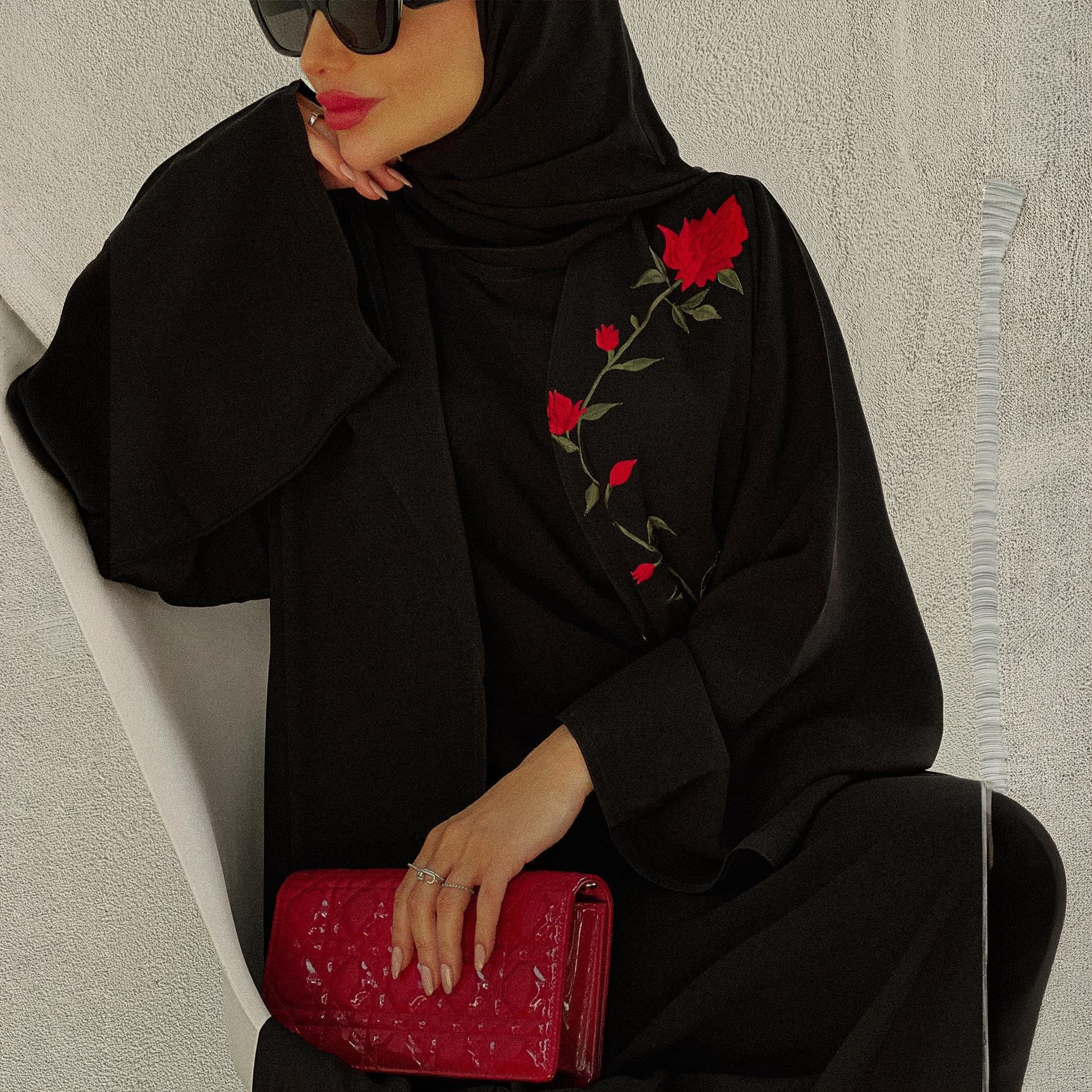 عباية سوداء كلاسيكية بتطريز ورود حمراء ناعم يضيف لمسة أنوثة راقية. قطعة تجمع بين البساطة والفخامة وتناسب إطلالات النهار والليل.