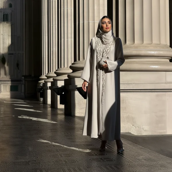 عباية فاخرة بتصميم راقٍ بلون عاجي هادئ، مزينة بتطريزات دقيقة تضيف لمسة فخامة وخفة لكل إطلالة.